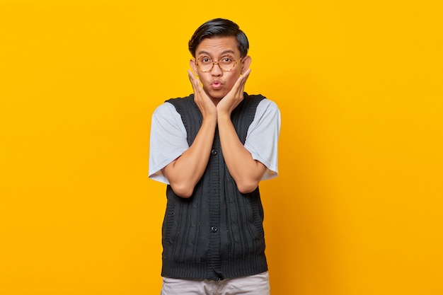 Portrait de jeune homme asiatique surpris regardant la caméra isolée sur fond jaune