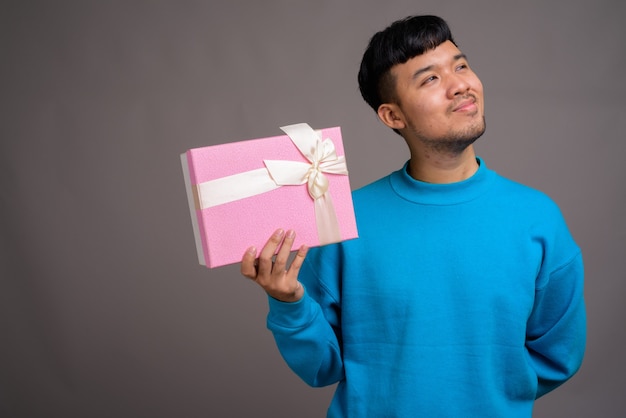 Portrait de jeune homme asiatique tenant une boîte-cadeau