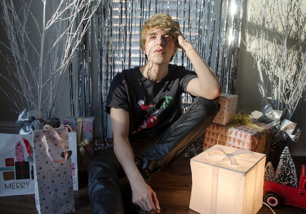 Photo portrait d'un jeune homme assis avec des cadeaux autour de lui