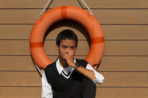 Photo portrait d'un jeune homme assis sur un sol en bois dur