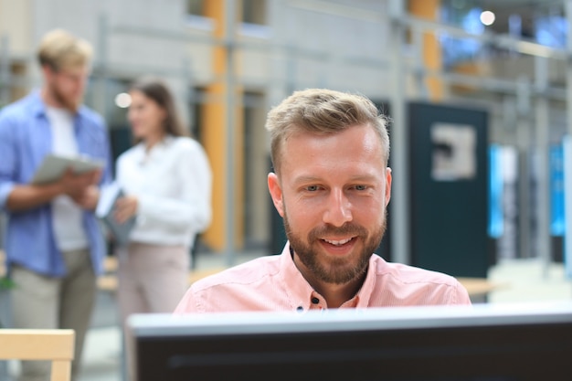 Portrait de jeune homme assis à son bureau au bureau, travaillant sur son PC