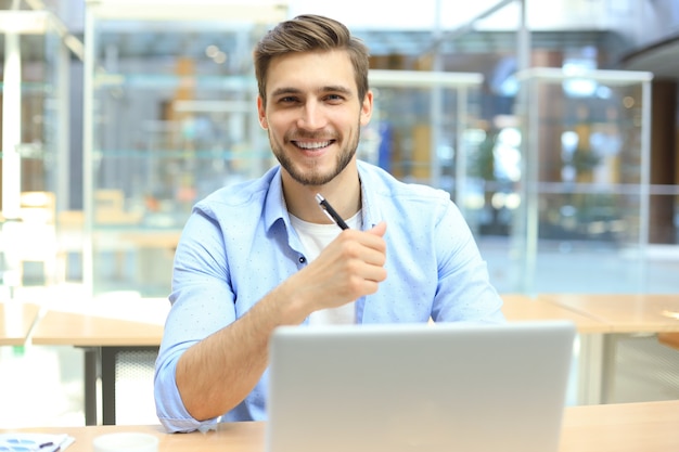 Portrait de jeune homme assis à son bureau au bureau.