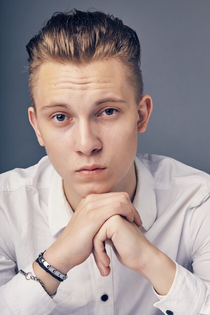 Portrait d'un jeune homme assis à une table sur une surface grise.