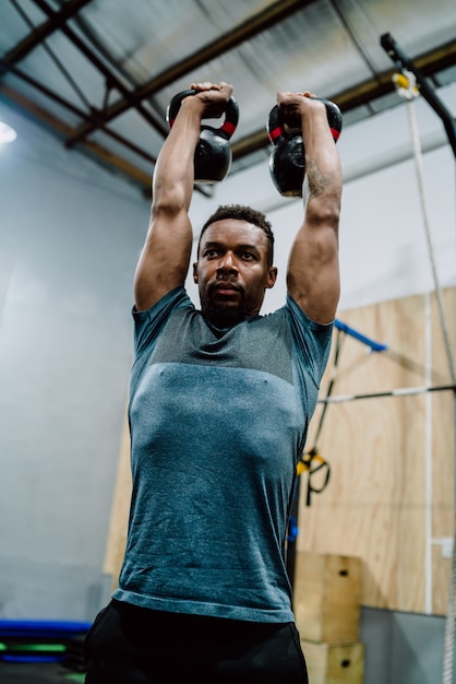 Portrait de jeune homme athlétique faisant de l'exercice avec crossfit kettlebel au gymnase