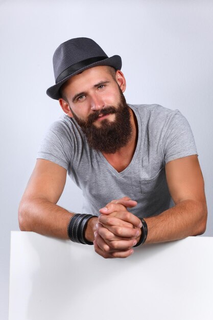 Portrait de jeune homme au chapeau debout près de blanc isolé sur fond blanc