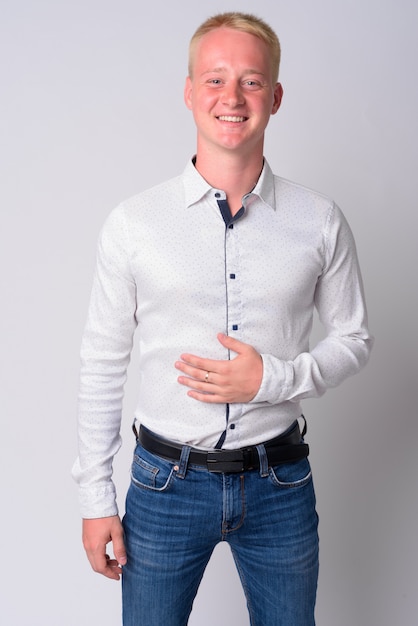 Portrait de jeune homme aux cheveux blonds contre un mur blanc