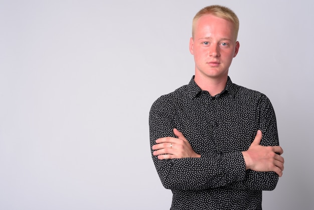 Portrait de jeune homme aux cheveux blonds contre un mur blanc