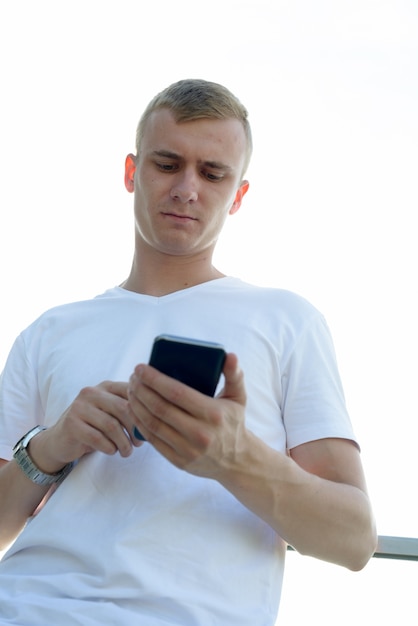 Portrait de jeune homme aux cheveux blonds contre vue sur le ciel clair à l'extérieur