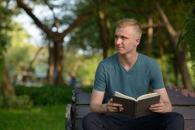 Portrait de jeune homme aux cheveux blonds dans le parc en plein air