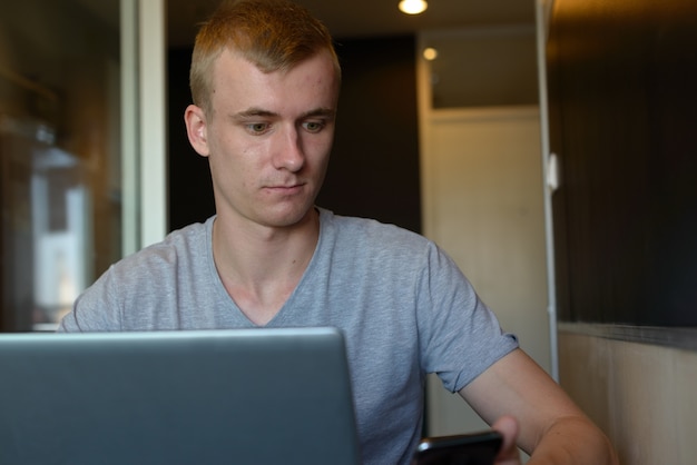 Portrait de jeune homme aux cheveux blonds se détendre à la maison à l'intérieur