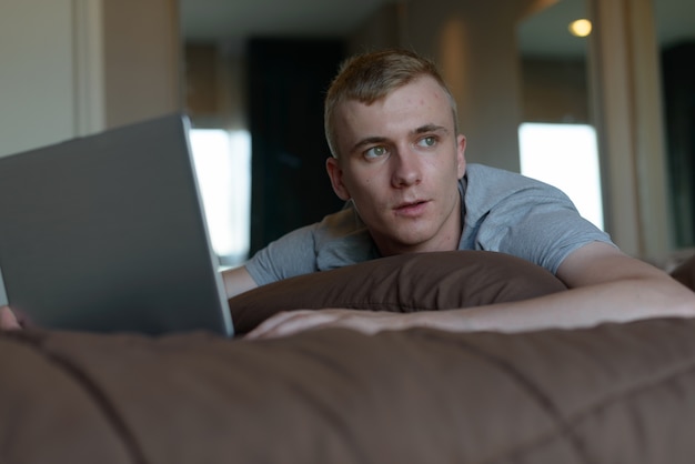 Portrait de jeune homme aux cheveux blonds se détendre à la maison à l'intérieur