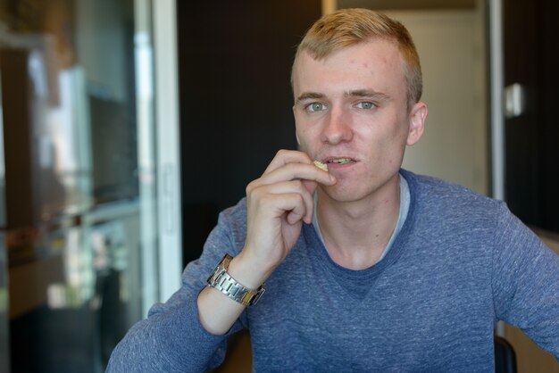 Portrait de jeune homme aux cheveux blonds se détendre à la maison à l'intérieur