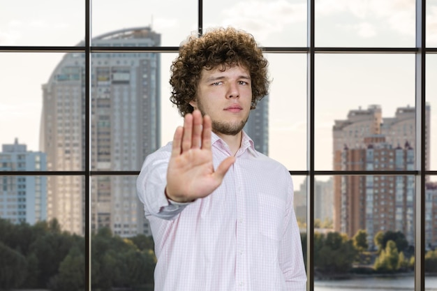 Photo portrait d'un jeune homme aux cheveux bouclés montre son signe de geste d'arrêt fenêtre à carreaux dans le