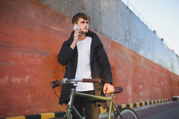 Portrait de jeune homme aux cheveux bruns debout avec vélo