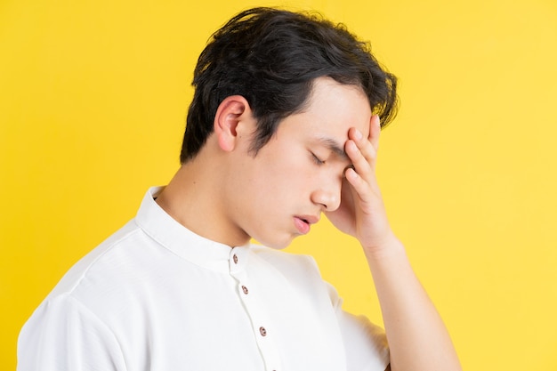 Portrait de jeune homme ayant mal à la tête sur jaune