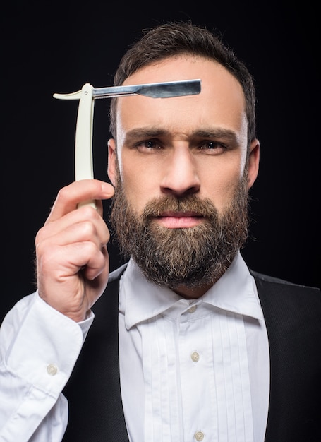 Portrait d&#39;un jeune homme barbu brutal avec un rasoir.