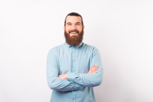 Portrait d'un jeune homme barbu confiant sourit à la caméra.