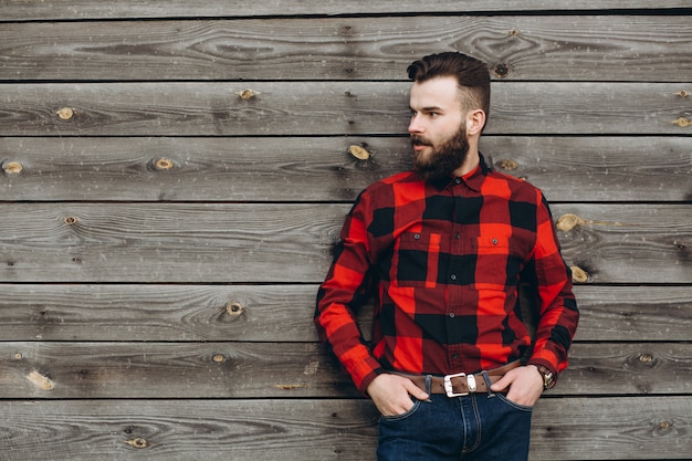 Portrait d&#39;un jeune homme barbu élégant, habillé en jeans et un vrai travailleur noir en chemise rouge.