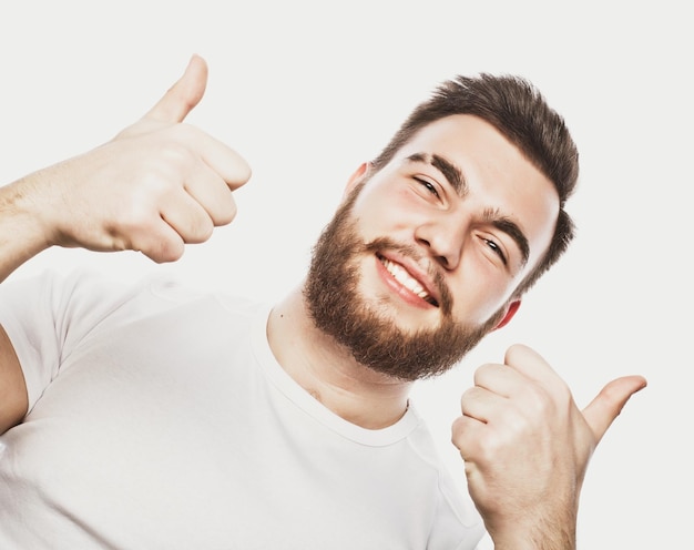 Portrait d'un jeune homme barbu joyeux montrant un geste correct isolé sur fond blanc