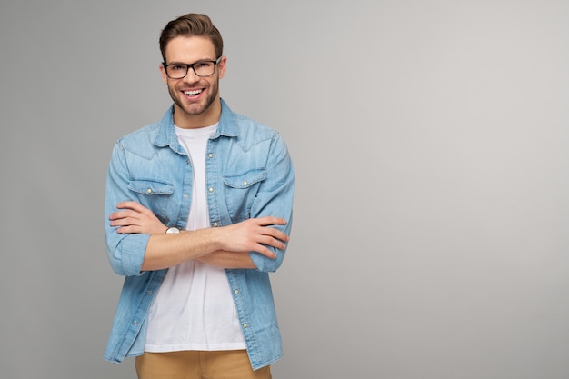 Portrait de jeune homme beau en chemise de jeans sur un mur léger