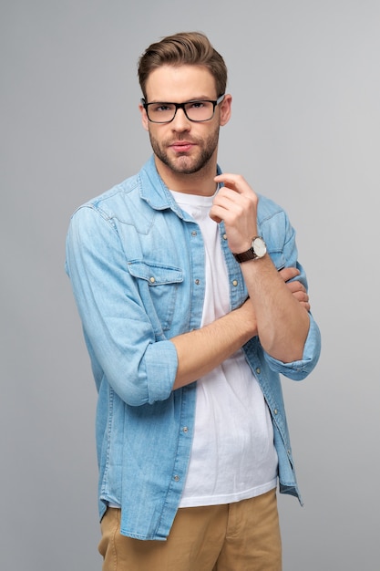 Portrait de jeune homme beau en chemise de jeans sur un mur léger