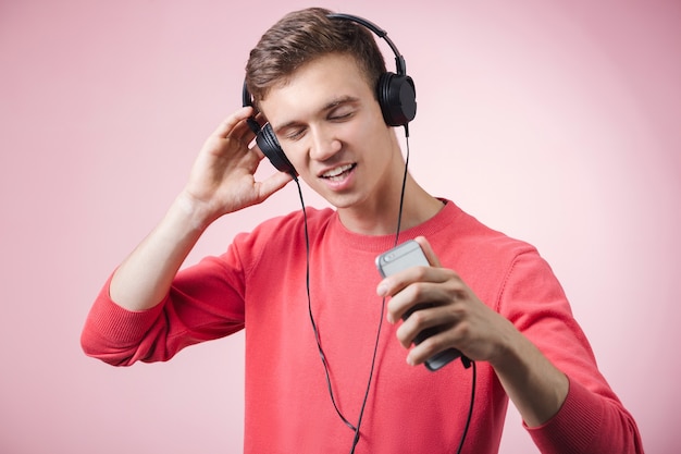 Portrait d'un jeune homme beau avec des écouteurs souriant et écoutant une musique