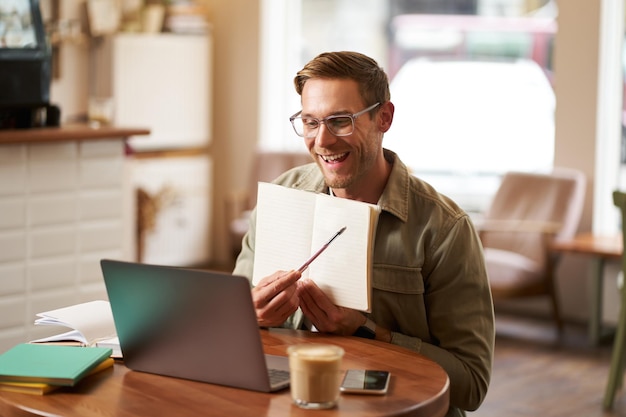 Portrait d'un jeune homme beau avec des lunettes, tuteur privé enseignant un étudiant en ligne, montrant son