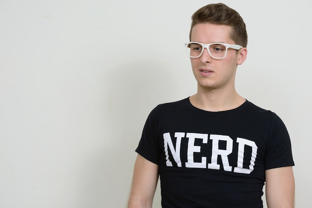 Portrait de jeune homme beau nerd contre le mur blanc