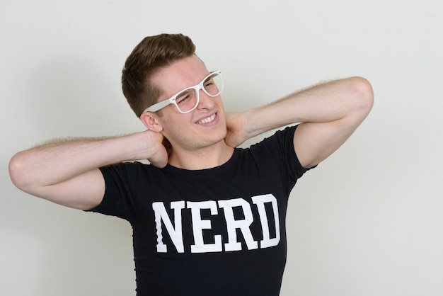 Portrait de jeune homme beau nerd contre le mur blanc