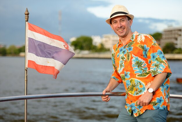 Portrait de jeune homme beau touriste au quai contre vue sur la rivière dans la ville de Bangkok