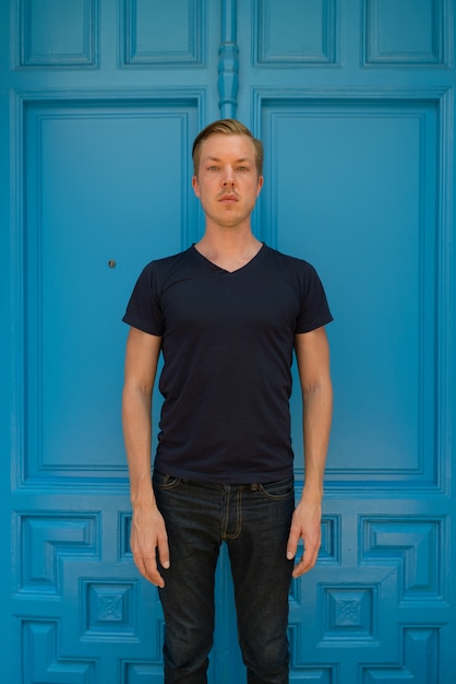 Portrait de jeune homme beau touriste debout devant la porte bleue