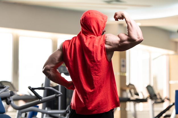 Portrait d'un jeune homme en bonne forme physique montrant son corps bien formé dans un sweat à capuche rouge Muscular Athletic Bodybuilder Fitness Model Posing After Exercises