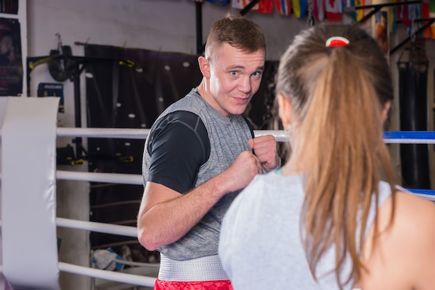 Portrait de jeune homme boxeur dans la formation de vêtements de sport avec une femme en ring de boxe régulier
