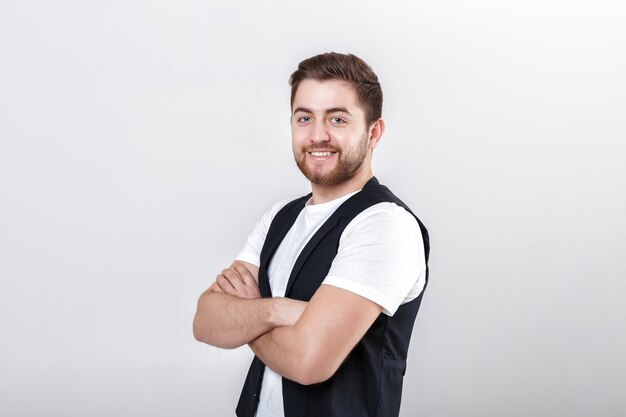 Portrait de jeune homme brune souriant séduisant en chemise blanche sur fond gris.