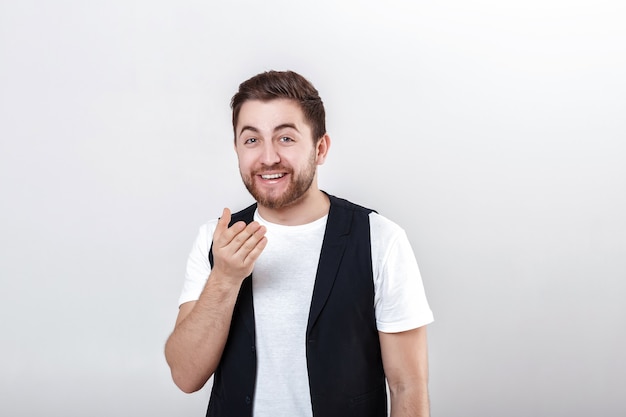 Portrait de jeune homme brune souriant séduisant en chemise blanche sur fond gris.