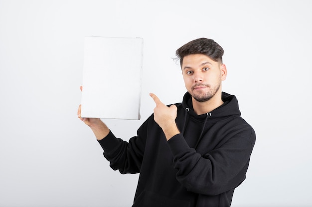 Portrait de jeune homme à capuche noir tenant une toile vide