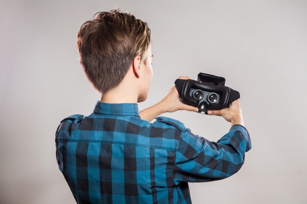 Portrait de jeune homme avec casque de réalité virtuelle. intérieur, isolé sur fond gris.