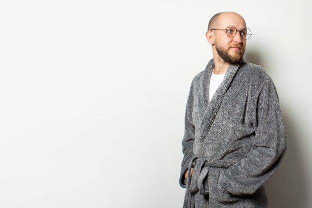 Portrait d'un jeune homme chauve avec une barbe dans un peignoir et des lunettes