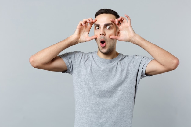 Portrait de jeune homme choqué dans des vêtements décontractés gardant la bouche grande ouverte, étirant les paupières