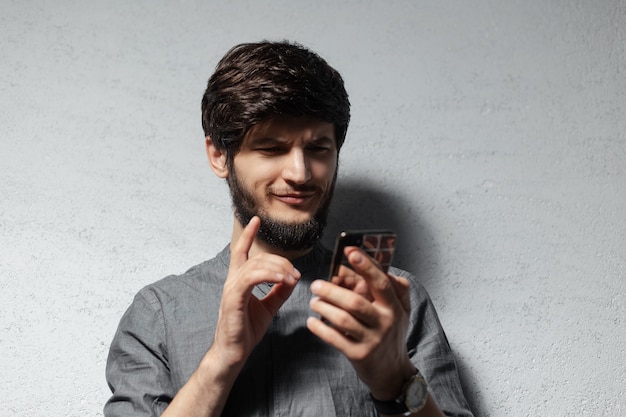 Portrait de jeune homme confiant à l'aide de smartphone.