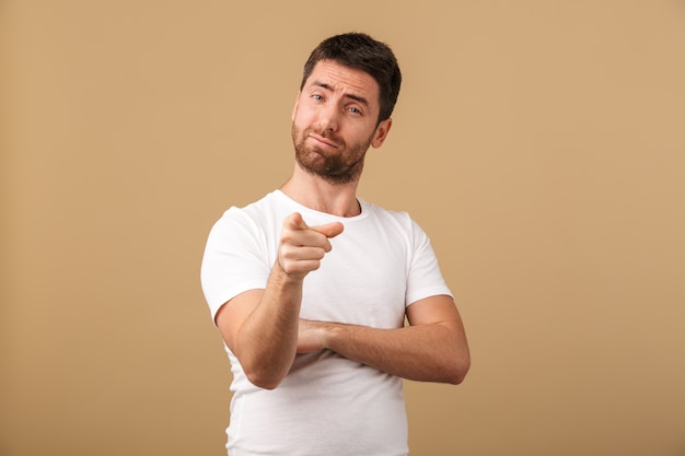 Portrait d'un jeune homme confiant habillé avec désinvolture debout isolé sur beige