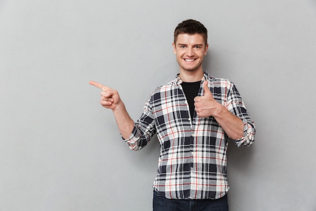 Portrait d'un jeune homme confiant pointant du doigt