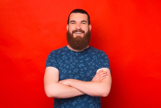 Portrait d'un jeune homme confiant souriant à la caméra sur fond rouge.