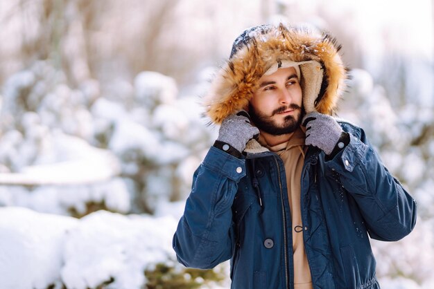 Portrait de jeune homme dans la forêt d'hiver enneigée Concept de voyages et de personnes de Noël