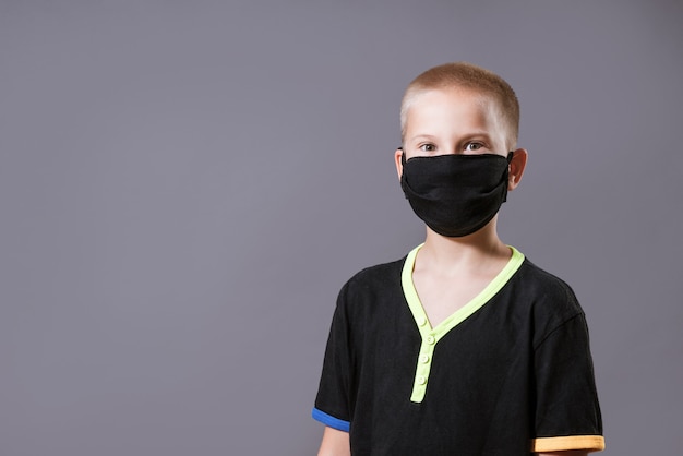 Portrait d'un jeune homme dans un masque de protection noir et tshirt sur un mur gris