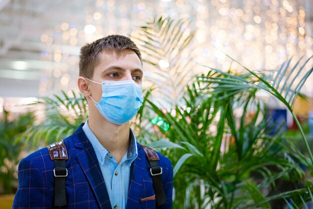 Portrait d'un jeune homme dans une veste et un masque médical dans un centre commercial