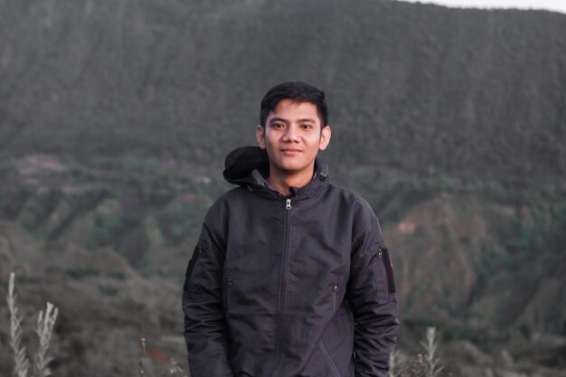 Portrait d'un jeune homme debout contre une montagne