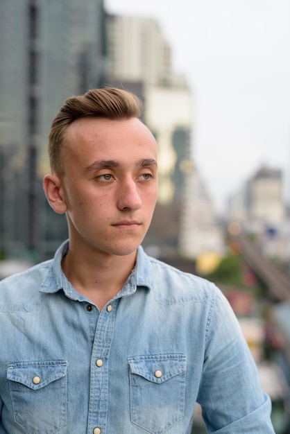 Portrait d'un jeune homme debout contre la ville