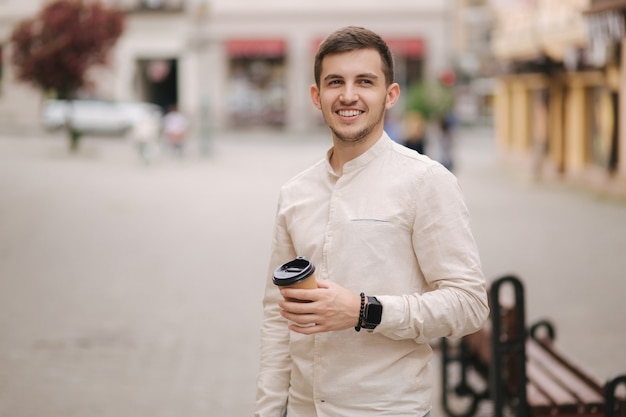 Portrait de jeune homme debout dans la ville avec une tasse de café