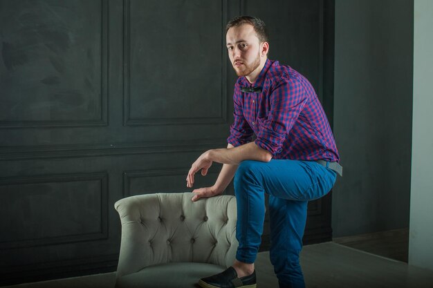 Photo portrait d'un jeune homme debout devant une chaise à la maison